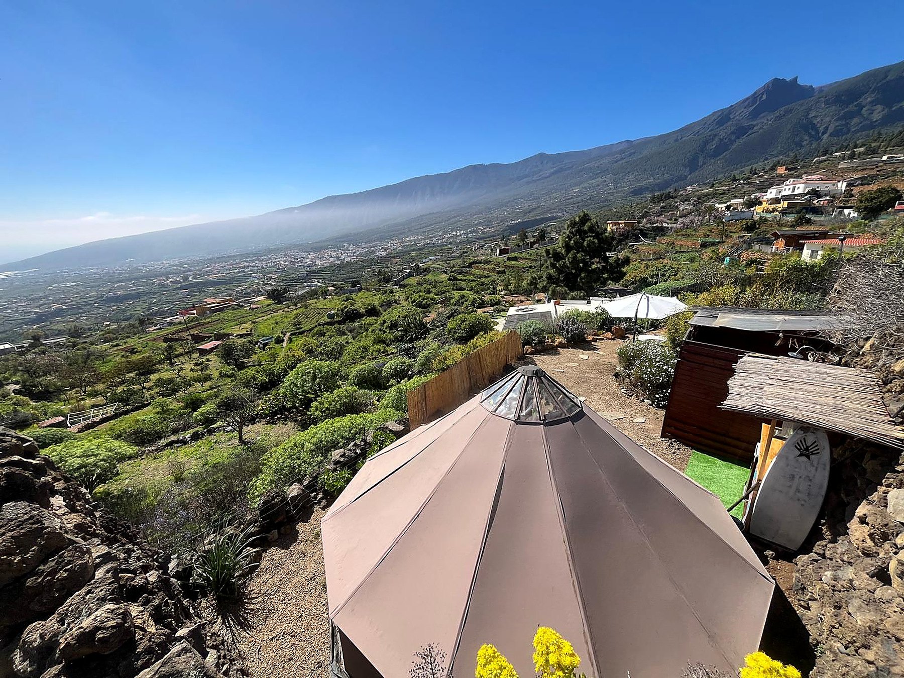 Grande tente polygonale sur une colline en terrasses surplombant la vallée et la montagne