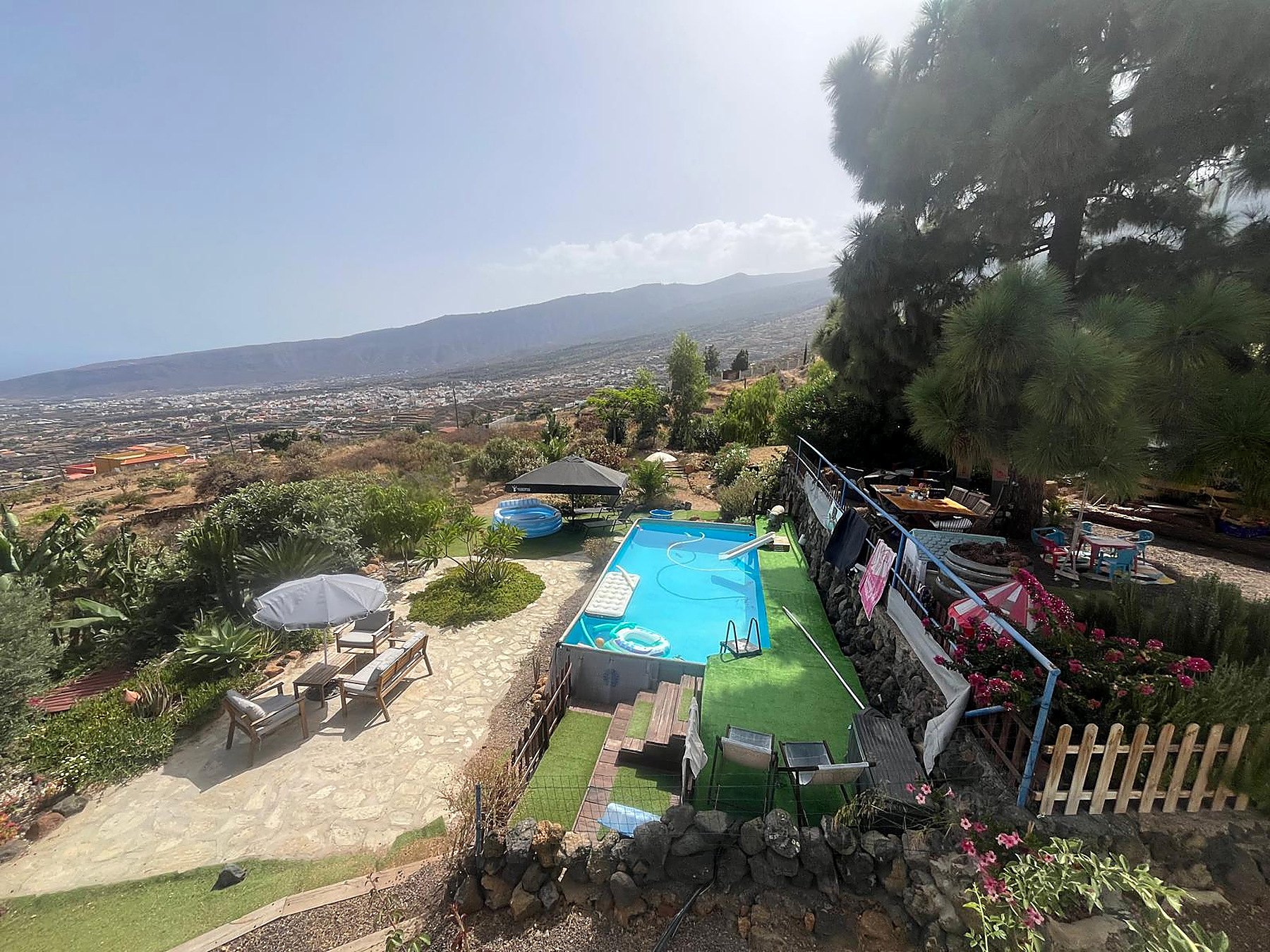 Vue panoramique depuis la propriété : piscine, terrasse, pins et vallée en contrebas