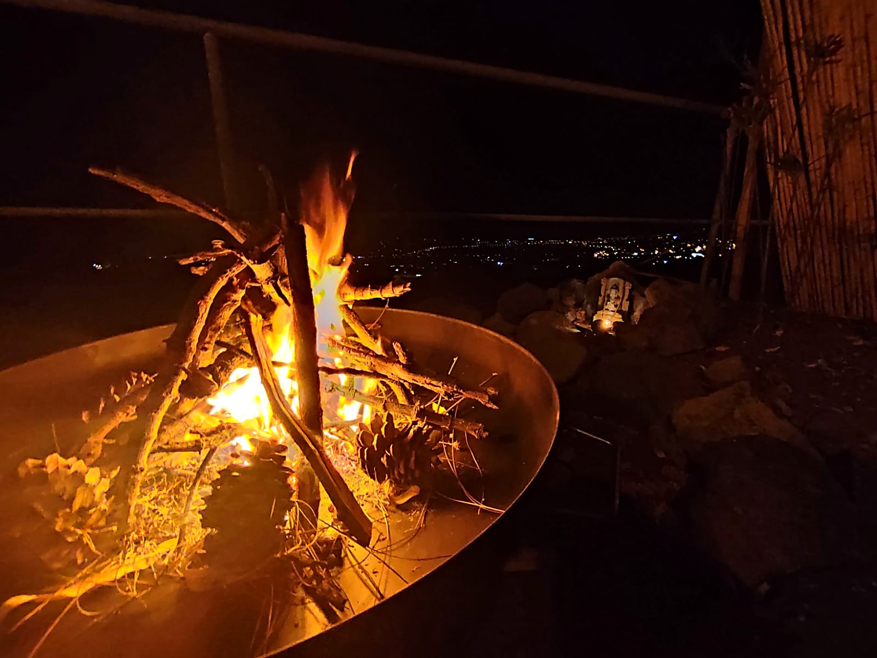 Feu de camp dans un grand brasero, lumières de la vallée en arrière-plan