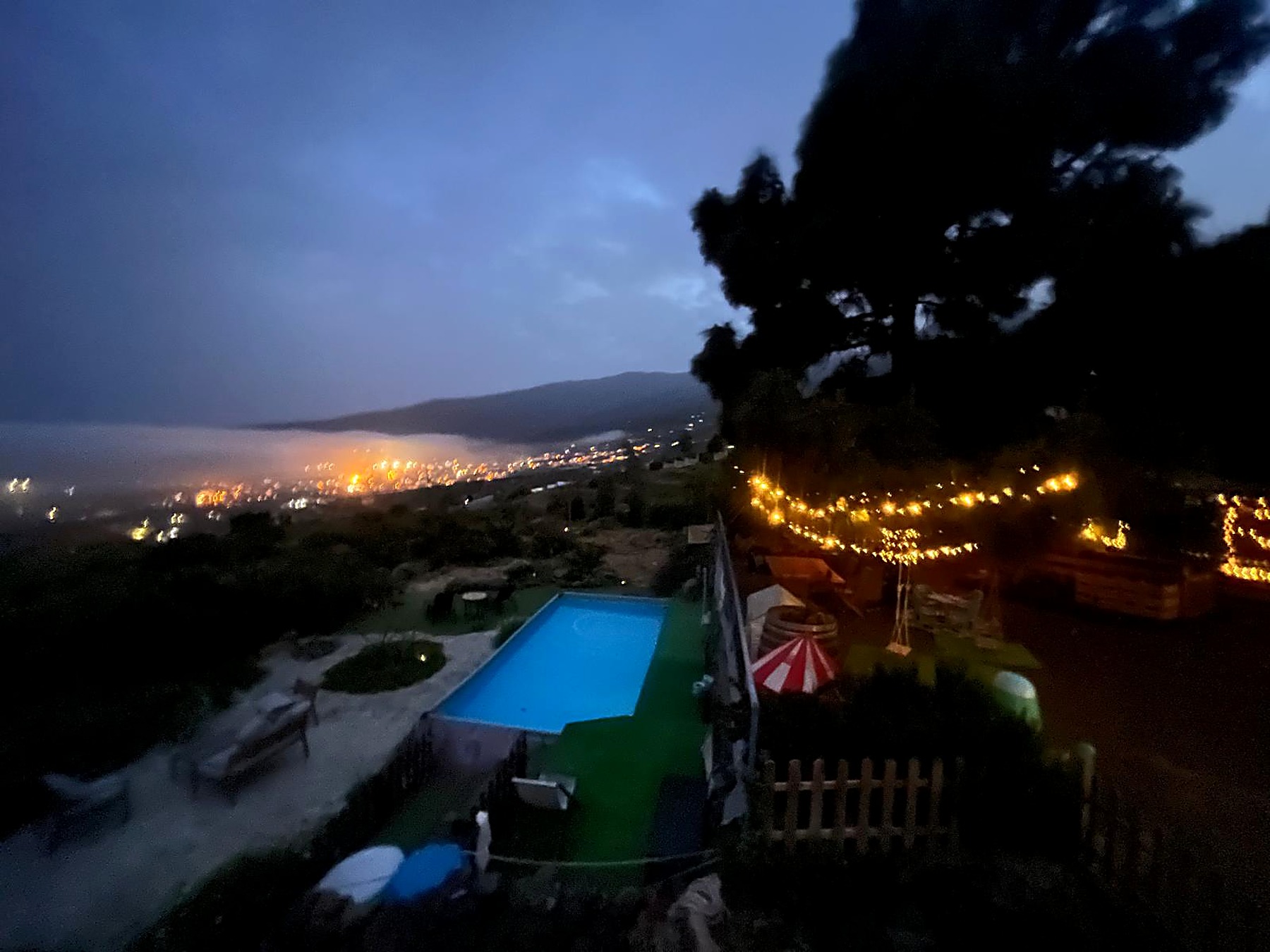 Piscine éclairée et guirlandes lumineuses au crépuscule au-dessus de la vallée