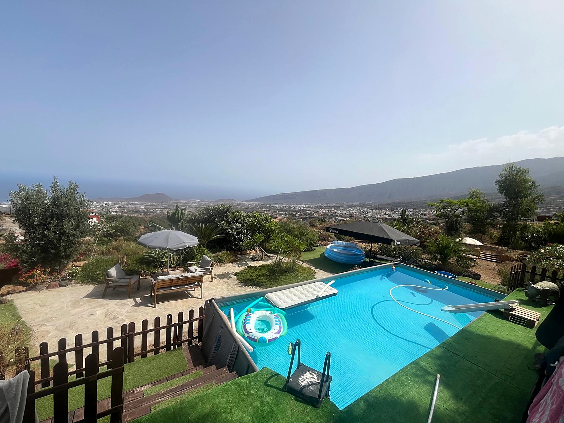 Piscine commune avec transats, parasols et vue sur la vallée et l'océan